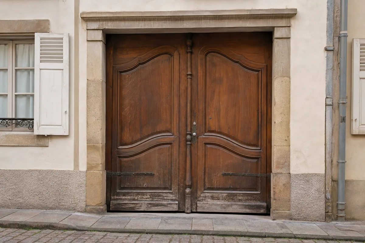 Porte d&rsquo;immeuble ancienne en bois massif dans une rue de Mulhouse, serrure encastrée patinée